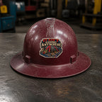 IT AIN'T GOING ANYWHERE 3-inch vinyl sticker on a worn maroon full-brim hard hat